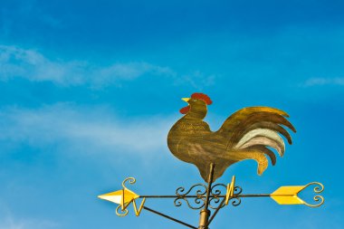 A cockerel wind vane against blue sky clipart