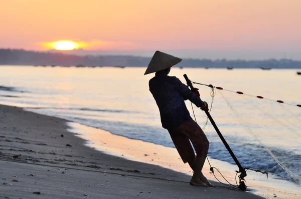 Silhouette of a fisherman on beach at sunrise — Stock Photo, Image