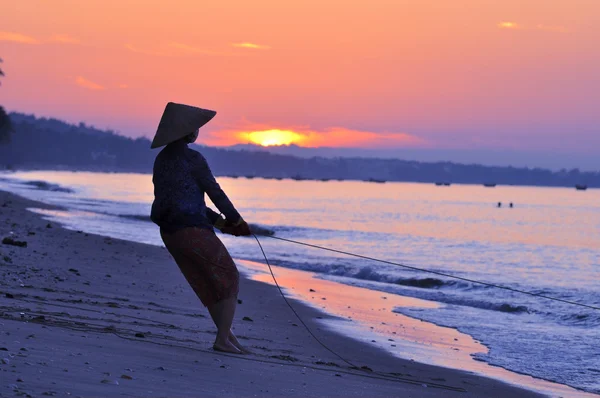 Silhouette di un pescatore sulla spiaggia all'alba — Foto Stock