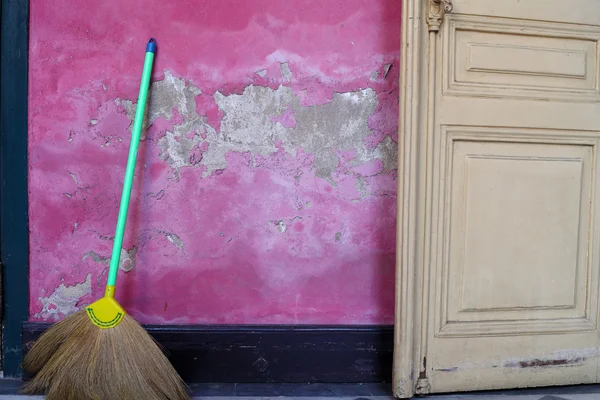 stock image Broom leaning against a grunge pink wall