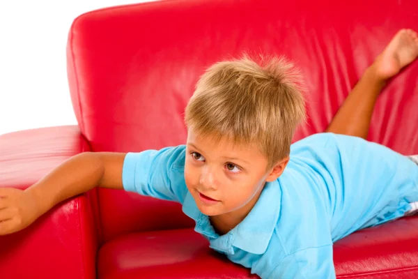 Хлопчик на червоному дивані — стокове фото