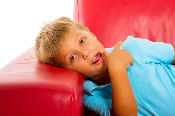 在红色沙发上的男孩 — 图库照片