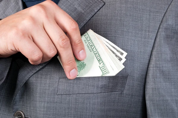 Male hand puts dollars in the pocket — Stock Photo, Image