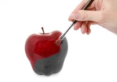 Female hand painting a fresh red apple which is partly black and clipart
