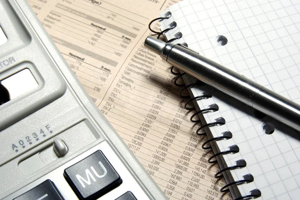 Financiële calculator, stalen pen en notitieblok opleggen krant — Stockfoto