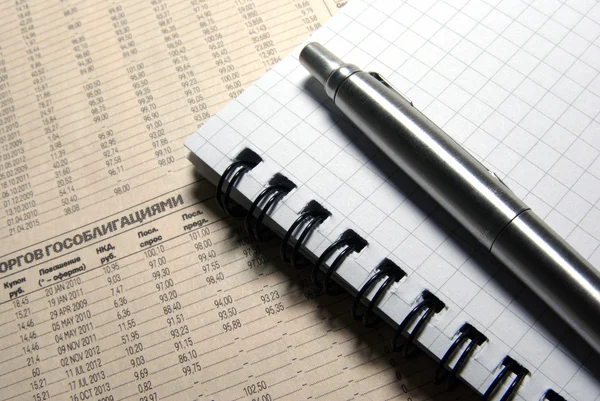 Pen en notitieblok opleggen van financiële krant. — Stockfoto