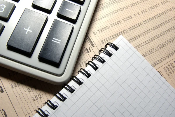 Calculadora y cuaderno de colocación en el periódico financiero . — Foto de Stock