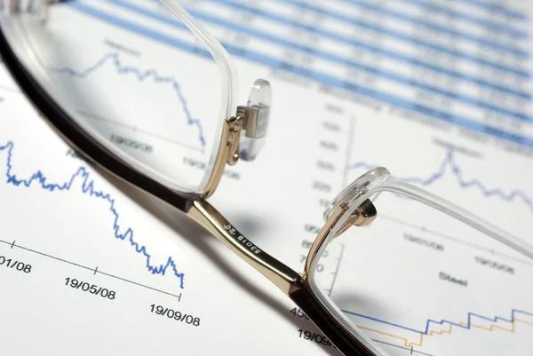Närbild på glasögon och ekonomisk rapport med diagram och data. — Stockfoto