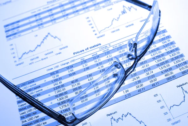 Glasses on printed stock report with graphs and tables. Stock Image