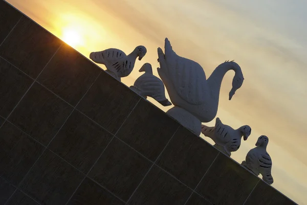 Silhueta de esculturas de cisne com pôr do sol no fundo . — Fotografia de Stock