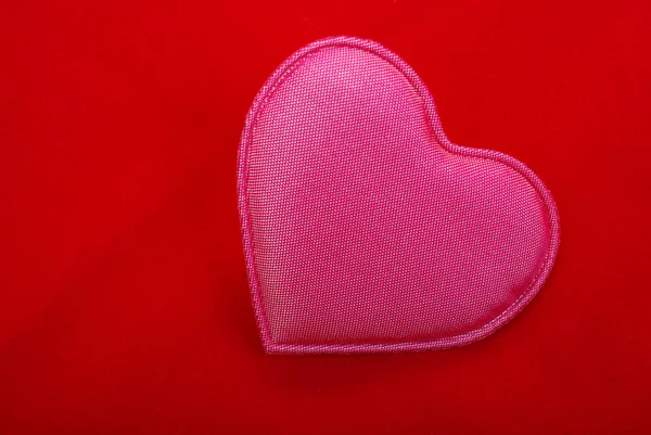 Różowy serce z bliska na białym tle na czerwonym tle teksturowane. — Zdjęcie stockowe