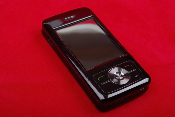 Glanzend zwart pda telefoon geïsoleerd op rode achtergrond. — Stockfoto