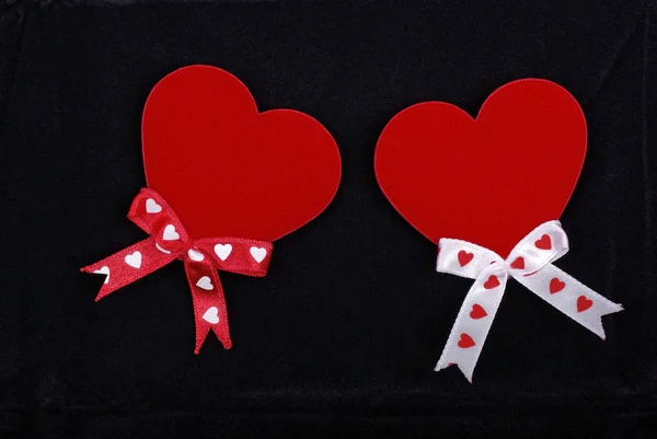 Two hearts with ribbons isolated on black velvet background. — Stock Photo, Image