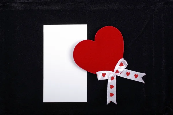 Rood hart met witte linten en lege kaart geïsoleerd op zwarte ve — Stockfoto