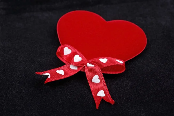 Coração vermelho com fitas de seda macro isolado em veludo preto backg — Fotografia de Stock