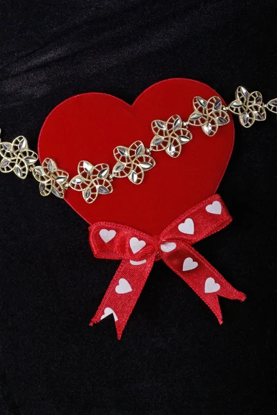 Goldenes Armband mit rotem Herz isoliert auf schwarzem Samtgrund — Stockfoto