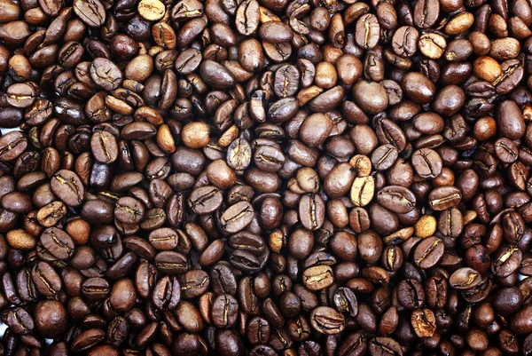 Haldy hnědé pražená kávová zrna jako pozadí nebo pozadí. — Stock fotografie