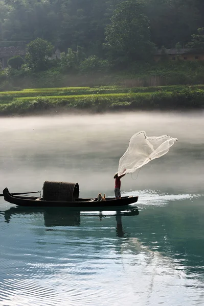 Fisherman casting net on river — Stock Photo, Image