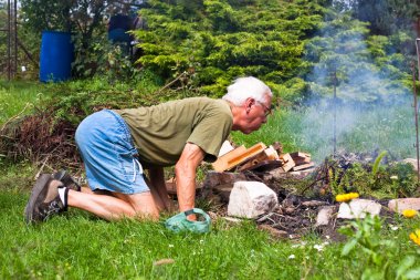 Senior man trying to make a bonfire clipart