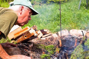 Senior man making bonfire clipart