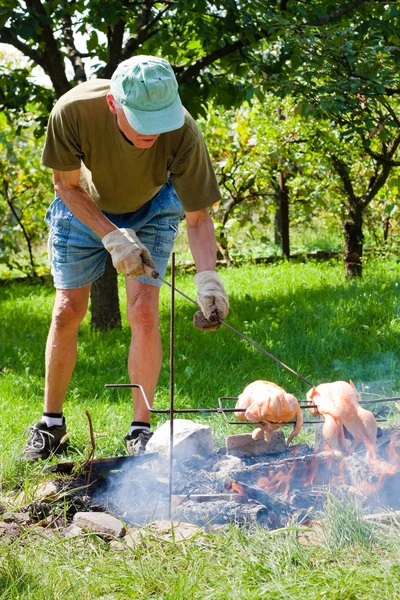 Senior man grilling chickens — Stock Photo, Image