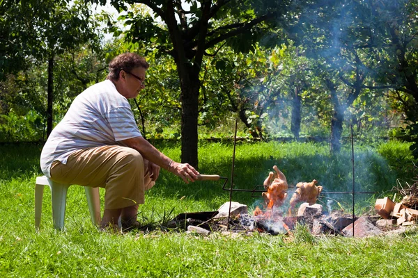 Seniorin grillt Hühner — Stockfoto