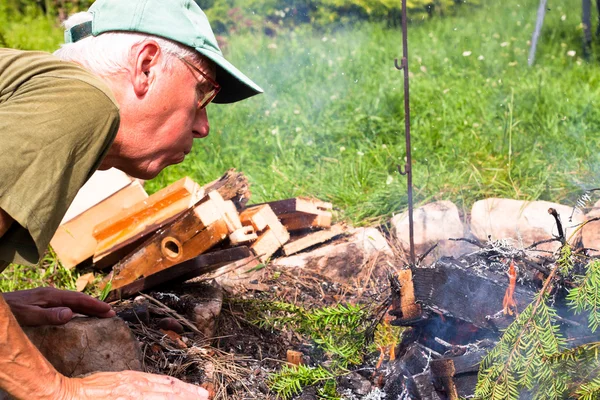 Senior man making bonfire — Stock Photo, Image