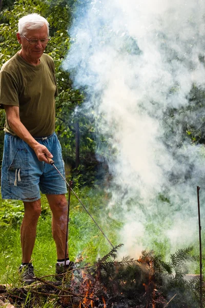Senior man and bonfire — Stock Photo, Image