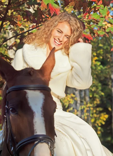 Glimlachend jonge bruid zittend op paard in bos — Stockfoto