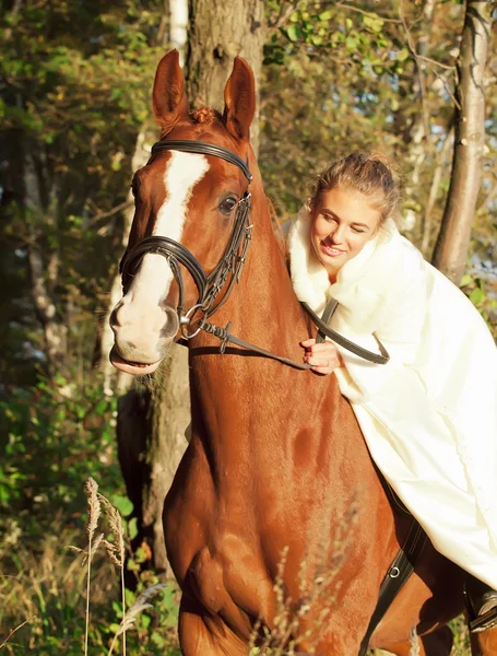 Young bride ride on sorrel horse in forest — Stock Photo, Image