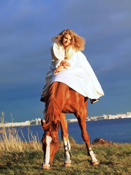 美丽的新娘骑在傍晚海湾的马 — 图库照片