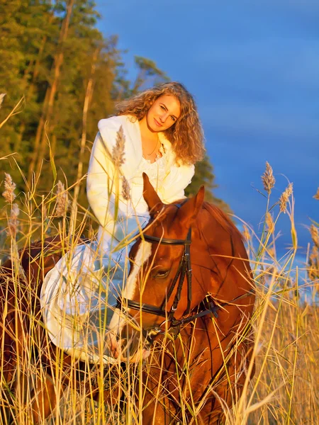 Hermosa novia sentada en caballo rojo al atardecer — Foto de Stock