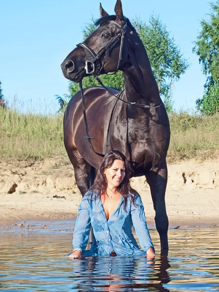 与黑色的马在水中的漂亮女人 — 图库照片