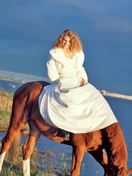 Bride ride on red horse in gulf at evening — Stock Photo, Image