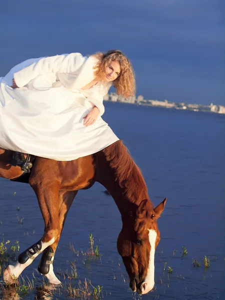 Bruden rida på röd häst i viken på kvällen — Stockfoto