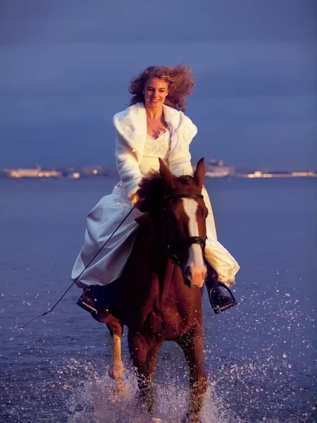 Bride ride on red horse in gulf at evening — Stock Photo, Image