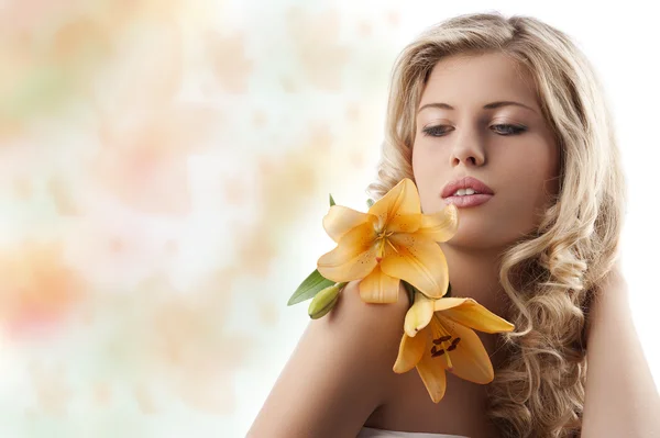 Blond curly girl with orange flower — Stock Photo, Image