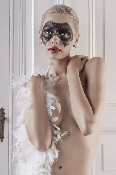 Vacker flicka klädd i endast en fjäderboa och en mask — Stockfoto