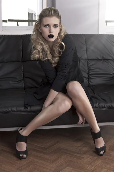 Елегантна дівчина сидить на чорному дивані — стокове фото