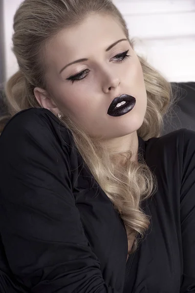 Blondes Mädchen auf Sofa mit schwarzen Lippen — Stockfoto