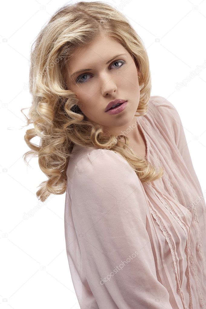 Blond young girl with curly hair looking towards camera with att