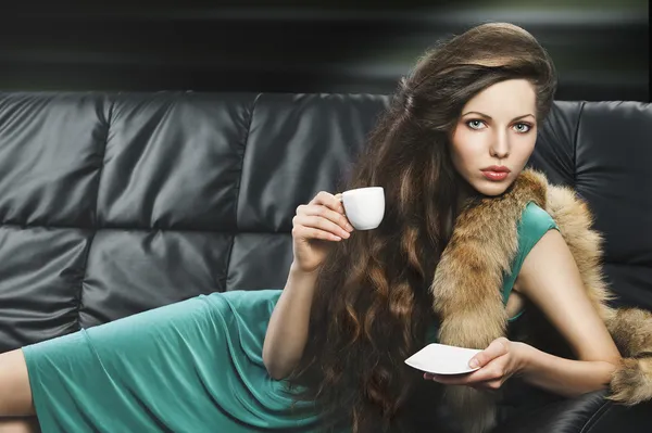 Κομψό κορίτσι στο πράσινο με Κύπελλο, λέει ψέματα στον καναπέ — Φωτογραφία Αρχείου