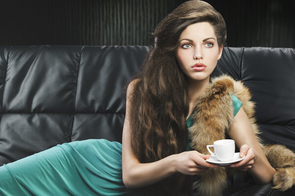 Young elegant girl in green with cup, she is in front of the len