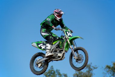 Motorcycle jumping against blue sky clipart