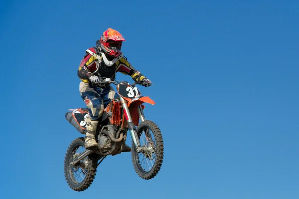 Motocicleta pulando contra o céu azul — Fotografia de Stock