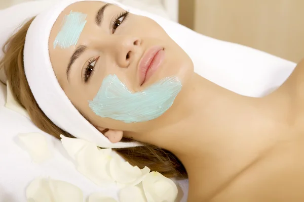 Jonge vrouw schoonheid huid masker behandeling krijgt op haar gezicht met — Stockfoto
