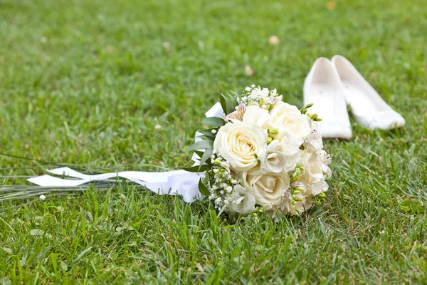 Bruiloft boeket op een gras en schoenen — Stockfoto