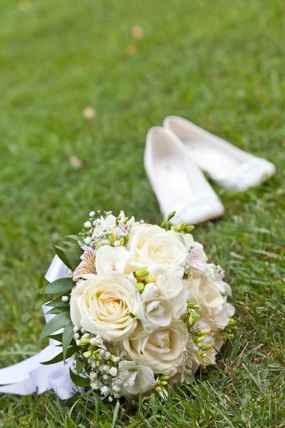 Wedding bouquet on a grass and shoes — Stock Photo, Image