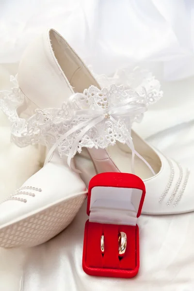 Bílé boty, podvazek a svatební prsteny — Stock fotografie