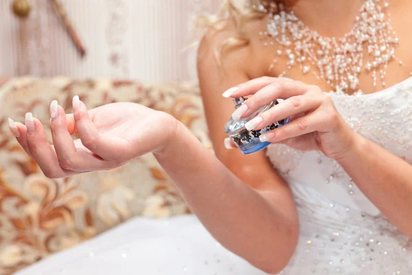 Mãos da noiva e uma garrafa de perfume — Fotografia de Stock